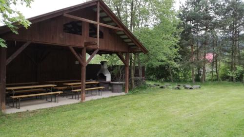 a wooden pavilion with benches and a grass field at Arenda Noclegi Niedzica in Niedzica