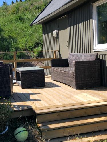 a wooden deck with two wicker chairs and a bench at FAXESTUGORNA in Abbekås