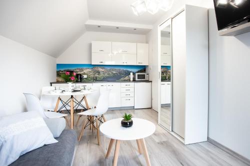 a kitchen and living room with a couch and tables at Apartamenty Pod Cisem in Kudowa-Zdrój