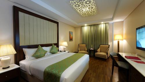 a hotel room with a large bed and a desk at Ramada by Wyndham Lahore Gulberg II in Lahore