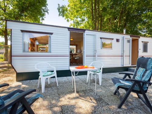 una pequeña casa blanca pequeña con sillas y mesa en Comfortable holiday home in Garderen en Garderen