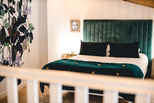 a bedroom with a bed with a green headboard at Les Précieuses Suites & Spa I in Avignon