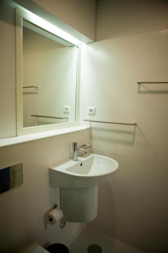 a white bathroom with a sink and a mirror at Hotel Comércio in Resende