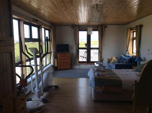 a living room with a bed and a couch and windows at Barkers Accommodation in Spanish Point