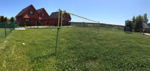 a large field with a house and a fence at Domki Letniskowe Błękit in Jastrzębia Góra