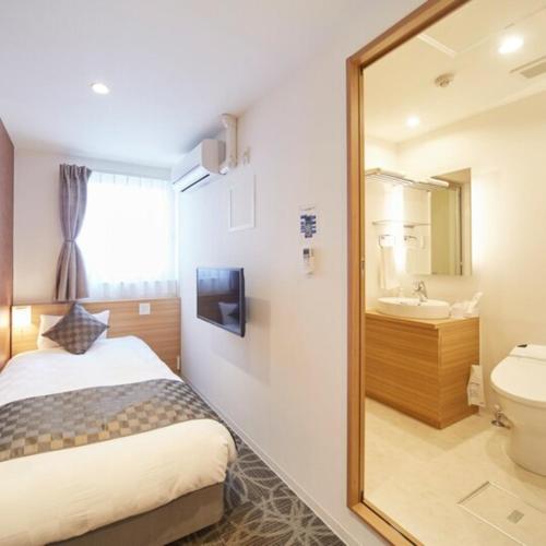 1 dormitorio con cama y espejo en Sakura Garden Hotel - Vacation STAY 79004 en Osaka