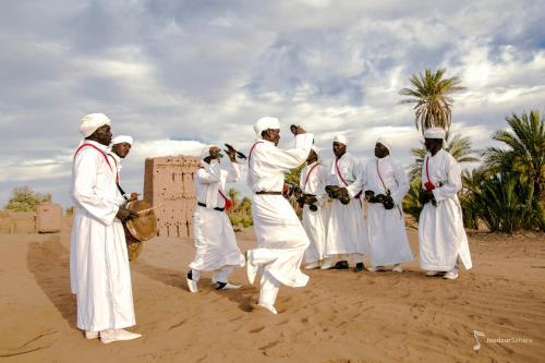 a group of men in white walking in the desert at Bivouac Joudour Sahara in Mhamid
