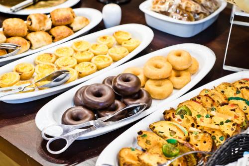 a table with several plates of pastries and other foods at Golden Tulip São João da Madeira in São João da Madeira