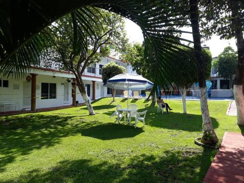 un patio con una mesa y una sombrilla en el césped en Hotel Quinta Paraiso, en Cocoyoc