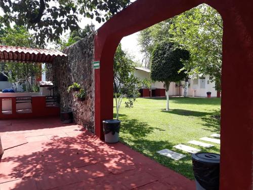 a red archway leading to a yard with a stone wall at Hotel Quinta Paraiso in Cocoyoc
