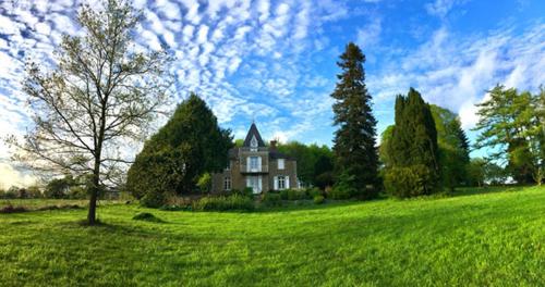 une maison au milieu d'un champ verdoyant dans l'établissement Les Gîtes du Château de Passillé, à Parigné