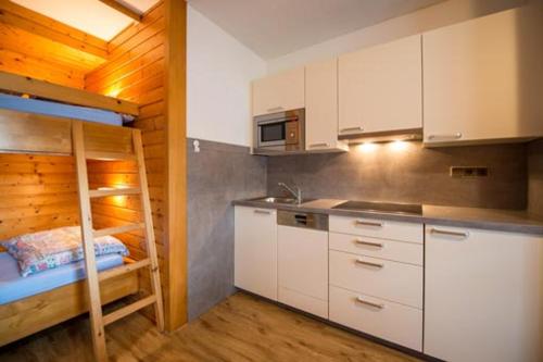 a kitchen with white cabinets and a bunk bed at Ferienhaus Nickl in Weissbriach