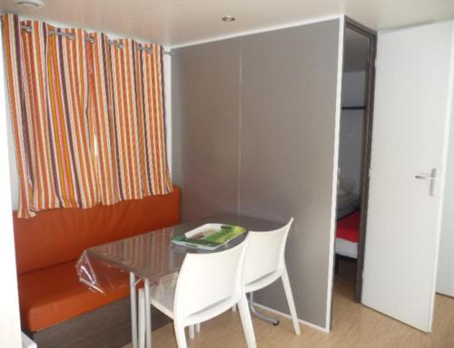 a dining room with a table and two white chairs at Location du Ranch in Algajola
