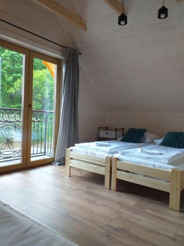 a bedroom with two beds and a large window at Domek pod Groniem in Mizerna