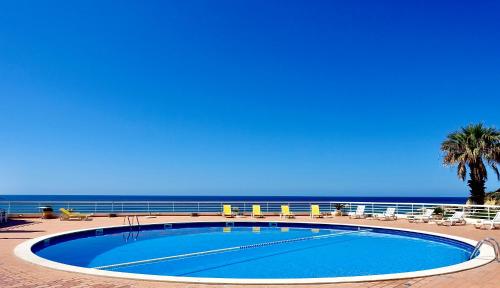 a swimming pool with chairs and the ocean in the background at Oura Ocean Front in Albufeira