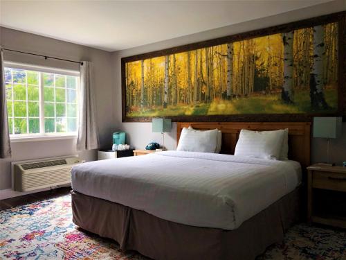 a bedroom with a large bed with a painting on the wall at Blue Elk Inn in Leavenworth