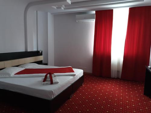 a hotel room with two beds and red curtains at Hotel Magic - City Center in Piteşti