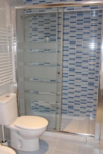 a bathroom with a toilet and a glass shower at Apartamento PLAYA ARBEYAL in Gijón