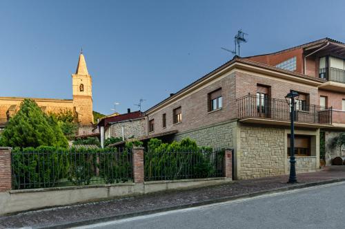 a brick building with a fence and a church at Casa Almoravid in Daroca de Rioja