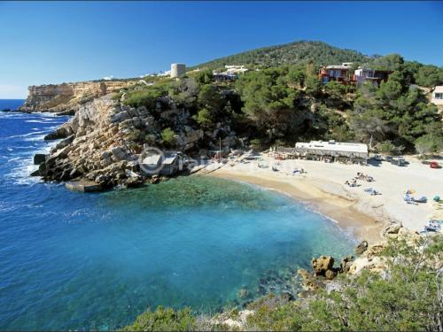 a beach with a group of people sitting on the beach at Casa Aguila Ibiza in Cala Vadella