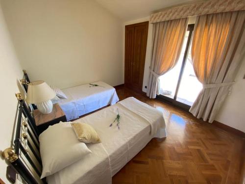 a bedroom with two beds and a large window at Villa Blanca con piscina a 15 minutos de Toledo in Olías del Rey