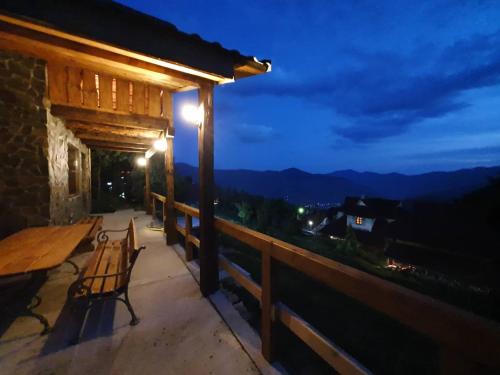 a wooden porch with a bench on a balcony at night at Rakhiv Plai in Rakhiv