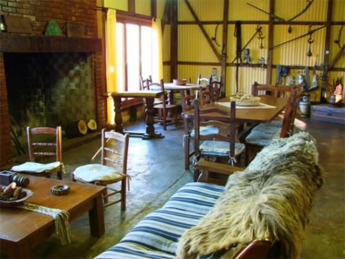 ein Wohnzimmer mit Tischen, Stühlen und einem Kamin in der Unterkunft Estancia Don Jose- GuenGuel in Río Mayo