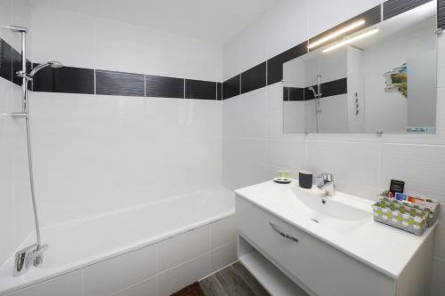 een witte badkamer met een wastafel en een bad bij Ron's Apartment in Colmar