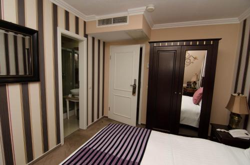 a bedroom with a bed and a door to a bathroom at Hotel Boutique Monaco in Bucharest