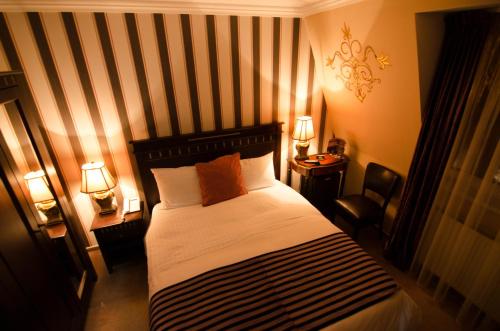 a bedroom with a bed with a striped wall at Hotel Boutique Monaco in Bucharest