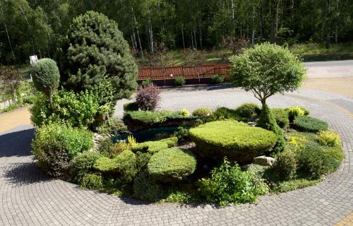 un jardín con arbustos verdes, árboles y un banco en Zajazd u Hermanów, en Olsztyn