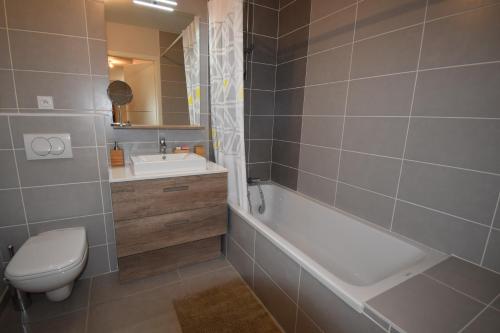 une salle de bain avec une baignoire, des toilettes et un lavabo dans l'établissement VAUJANYLOCATIONS - Domaine du Pâtre, à Vaujany