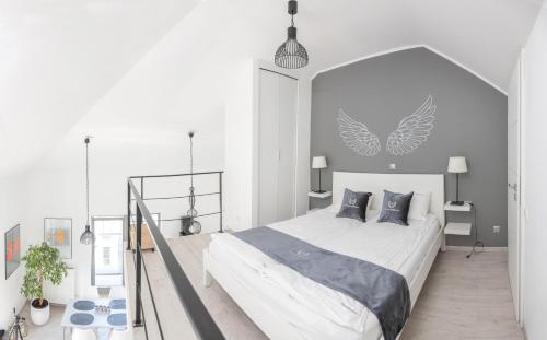 a white bedroom with a large bed with gray pillows at Apartamenty Gdańsk EU - Waterlane in Gdańsk