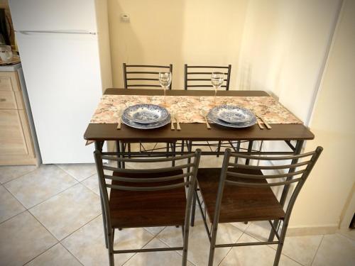 stół z 2 krzesłami i 2 talerzami oraz kieliszki do wina w obiekcie Kallithea studio w mieście Kallithea