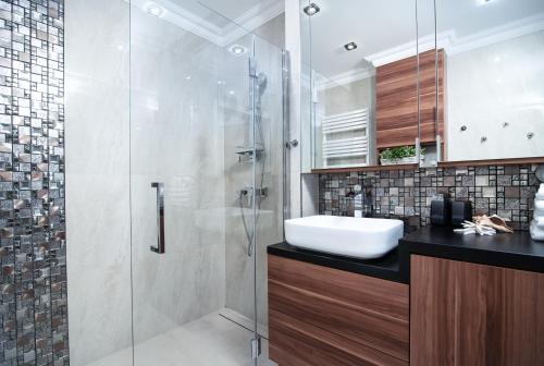 uma casa de banho com uma cabina de duche em vidro e um lavatório. em Apartamenty Relax em Władysławowo
