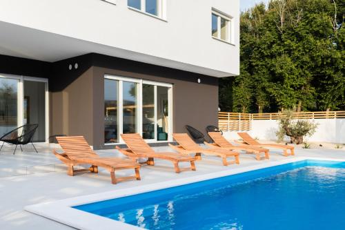 a group of chairs sitting next to a swimming pool at Villa Belveder in Pag