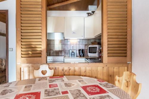 une cuisine avec une table et une cuisine avec un micro-ondes dans l'établissement Studio les Granges - Vue montage et village, Centre la Clusaz - AravisTour, à La Clusaz