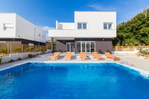 a house with a swimming pool in front of a house at Villa Belveder in Pag