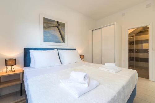 a bedroom with a large white bed with towels on it at Villa Belveder in Pag