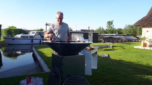 a man is cooking on a bbq grill at Villa Pura Vida in Oud-Ade