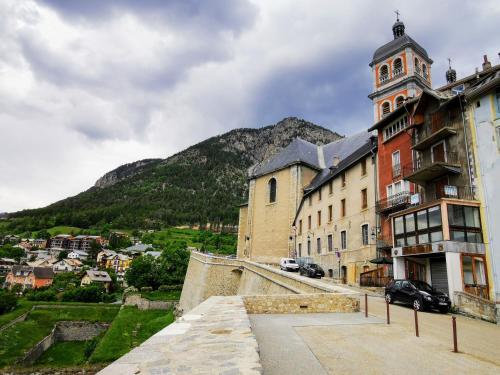 un bâtiment avec une tour avec une montagne en arrière-plan dans l'établissement Loft avec coin montagne, à Briançon