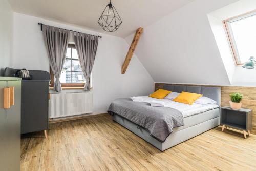 a bedroom with a bed and two windows at Przystanek Jantar - pokoje i apartamenty in Jantar