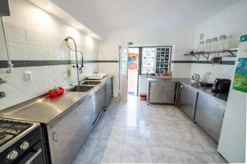 a large kitchen with stainless steel counter tops and a large sink at Surf Yoga Ericeira Guest House in Ericeira