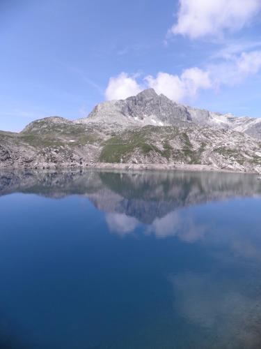 a mountain is reflected in the water of a lake at Appartments Haus Monika in Schoppernau