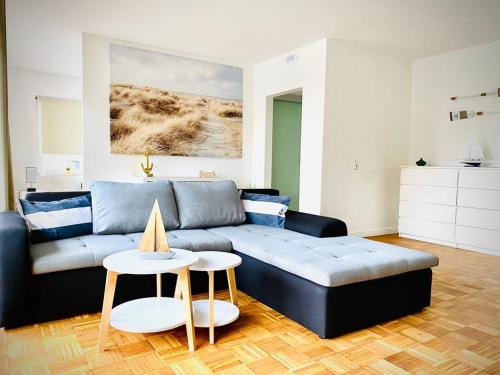 a living room with a blue couch and a table at FeWo MEERESBRISE - Familie- Hunde - Strandnah - Garten-Seeblick - Sauna & Wellness in Sierksdorf