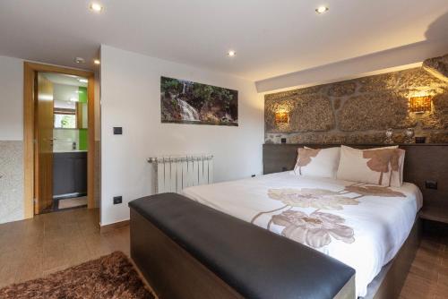 a bedroom with a large bed and a stone wall at Casa da Fonte Gerês in Campo do Gerês