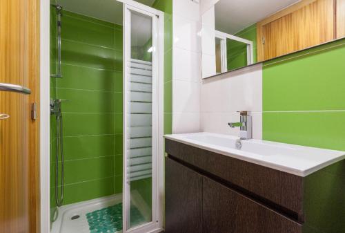 a green and white bathroom with a sink and a shower at Casa da Fonte Gerês in Campo do Gerês