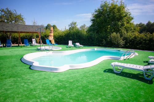a large swimming pool in a grassy yard with two chairs at Pansionat Bogema in Truskavets