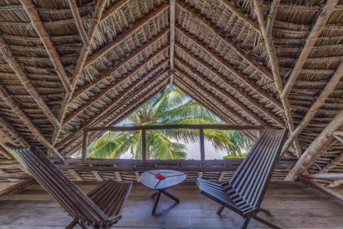 two chairs and a table in a room with a palm tree at SeVi Boutique Hotel in Matemwe