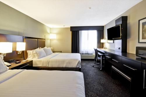 a hotel room with two beds and a desk at Holiday Inn Express Romulus / Detroit Airport by IHG in Romulus